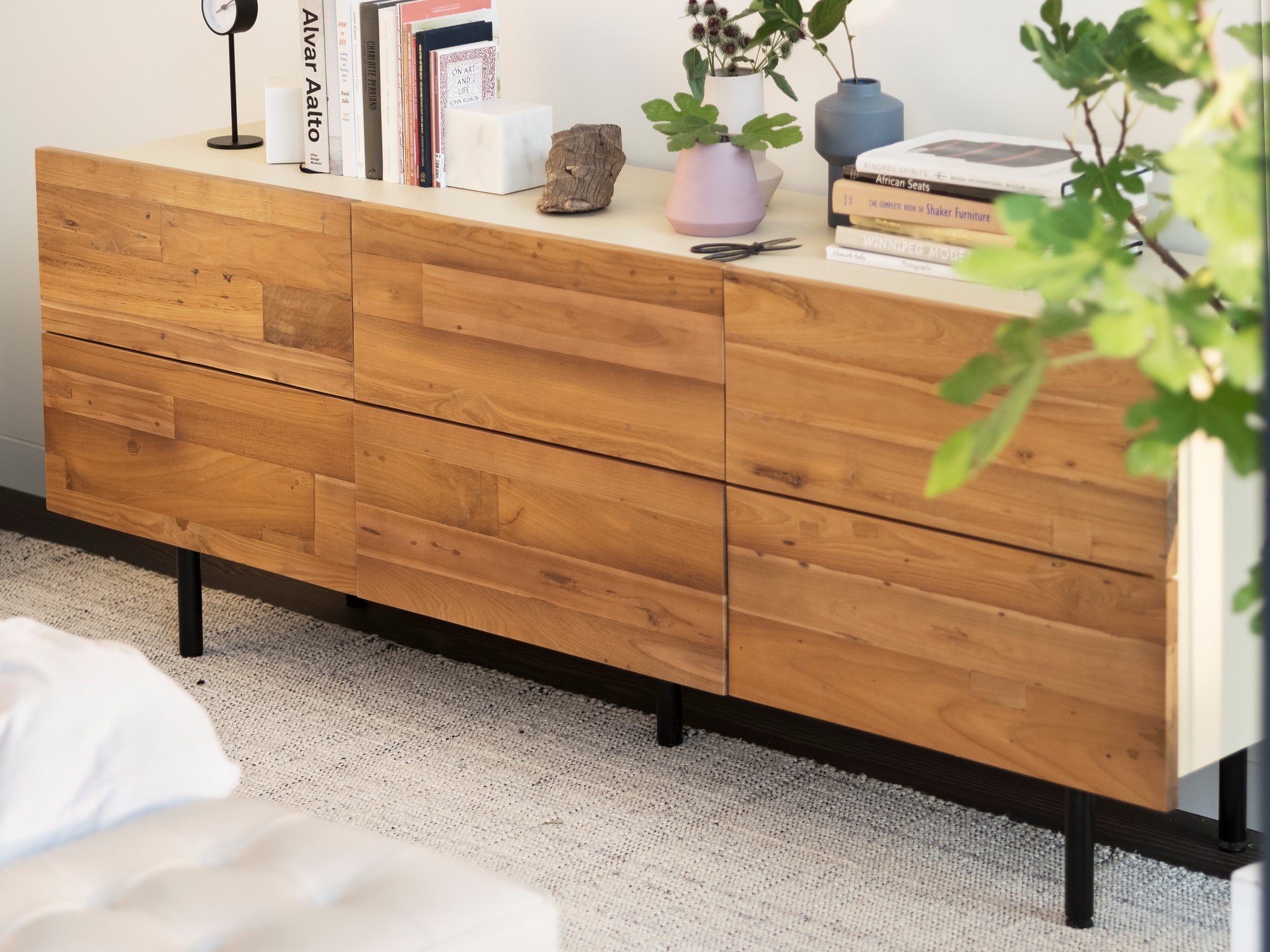 The Reclaimed Teak Low Dresser on a beige rug with books and vases lining the top